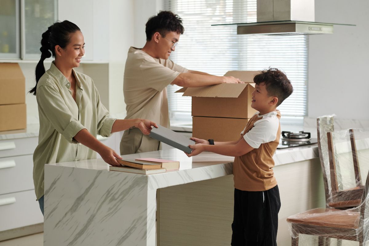 Family unpacking boxes together in a bright modern condominium kitchen