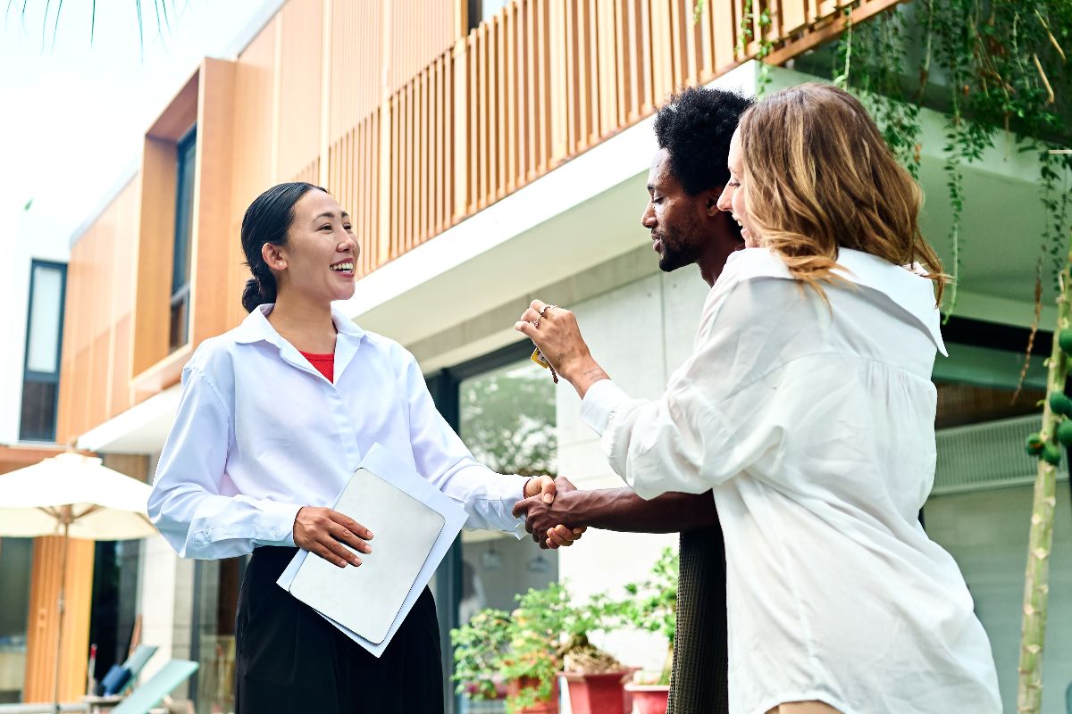Real estate agent welcoming an expat couple outside a modern condominium property