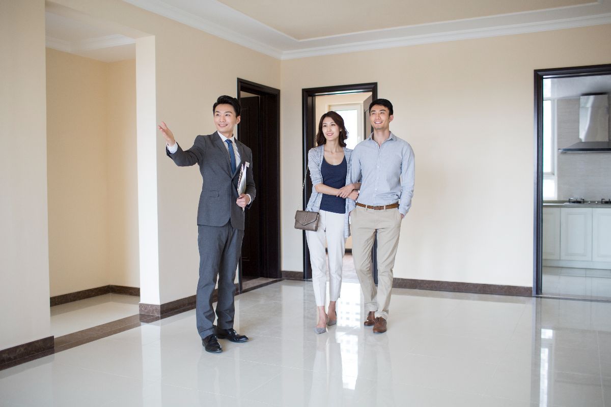 Property agent touring a spacious condominium unit with prospective buyers