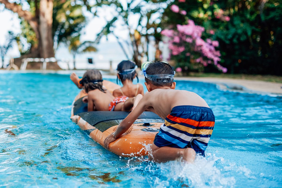 Children playing together with a pool float during a group activity in an outdoor swimming pool