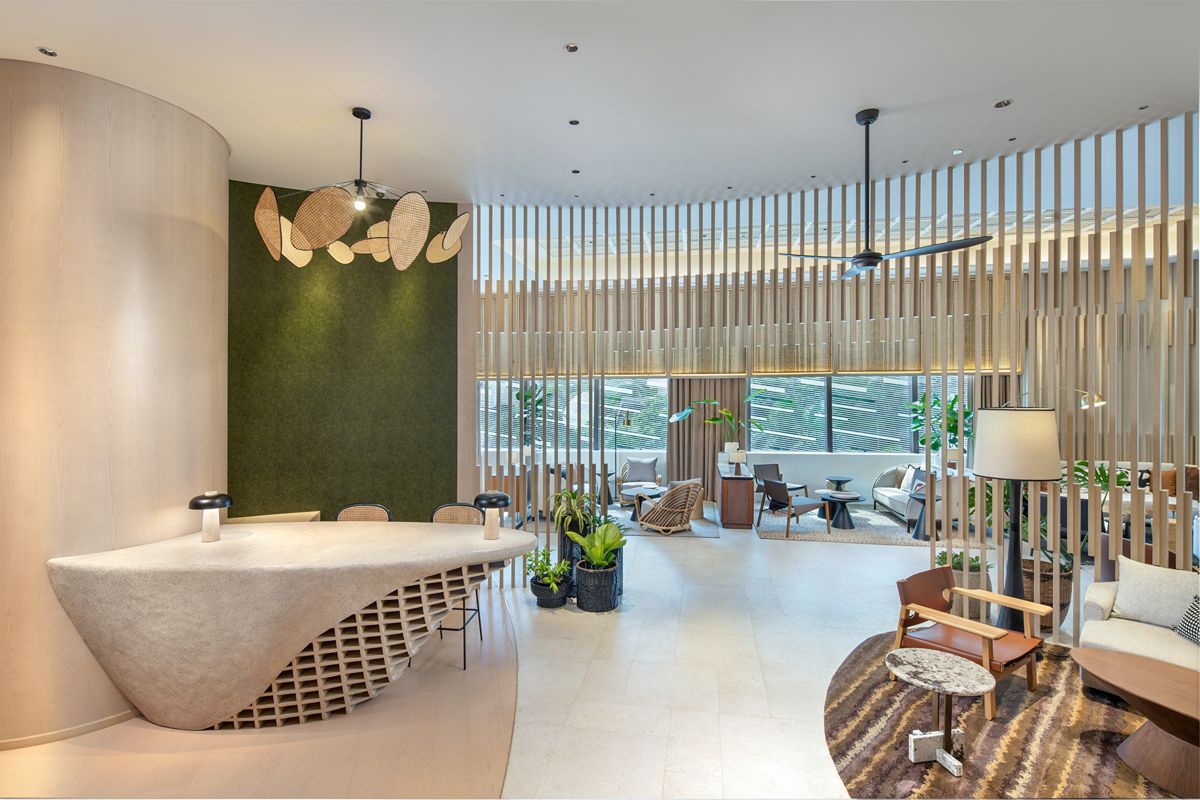 Open condominium lounge with a curved counter, comfortable seating areas, indoor plants, and floor-to-ceiling windows