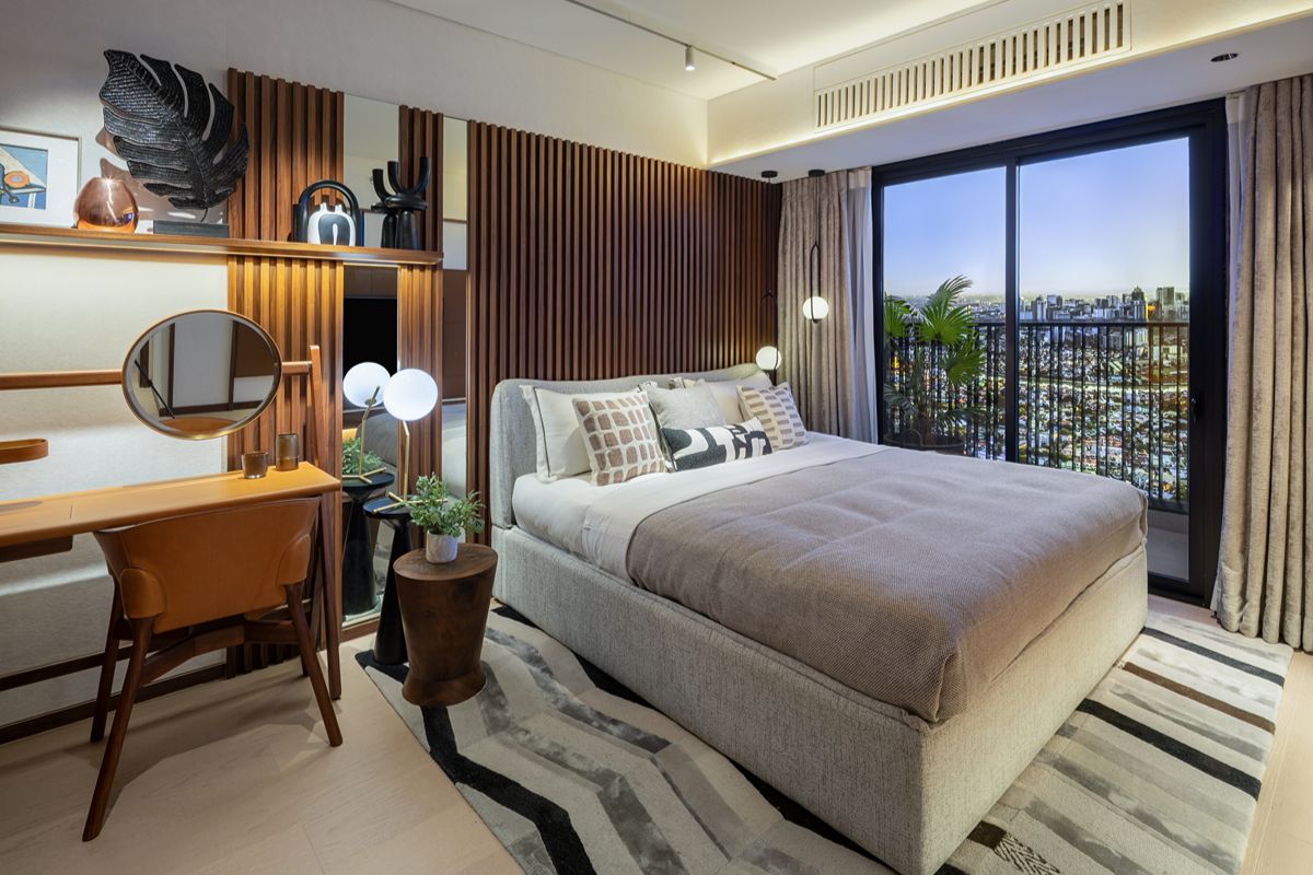 Condominium bedroom with an upholstered bed, built-in desk, wood slat wall panels, and sliding glass doors leading to a balcony